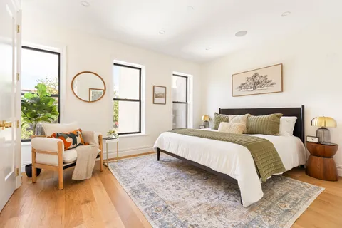 a spacious bedroom with a bed a mirror and a window