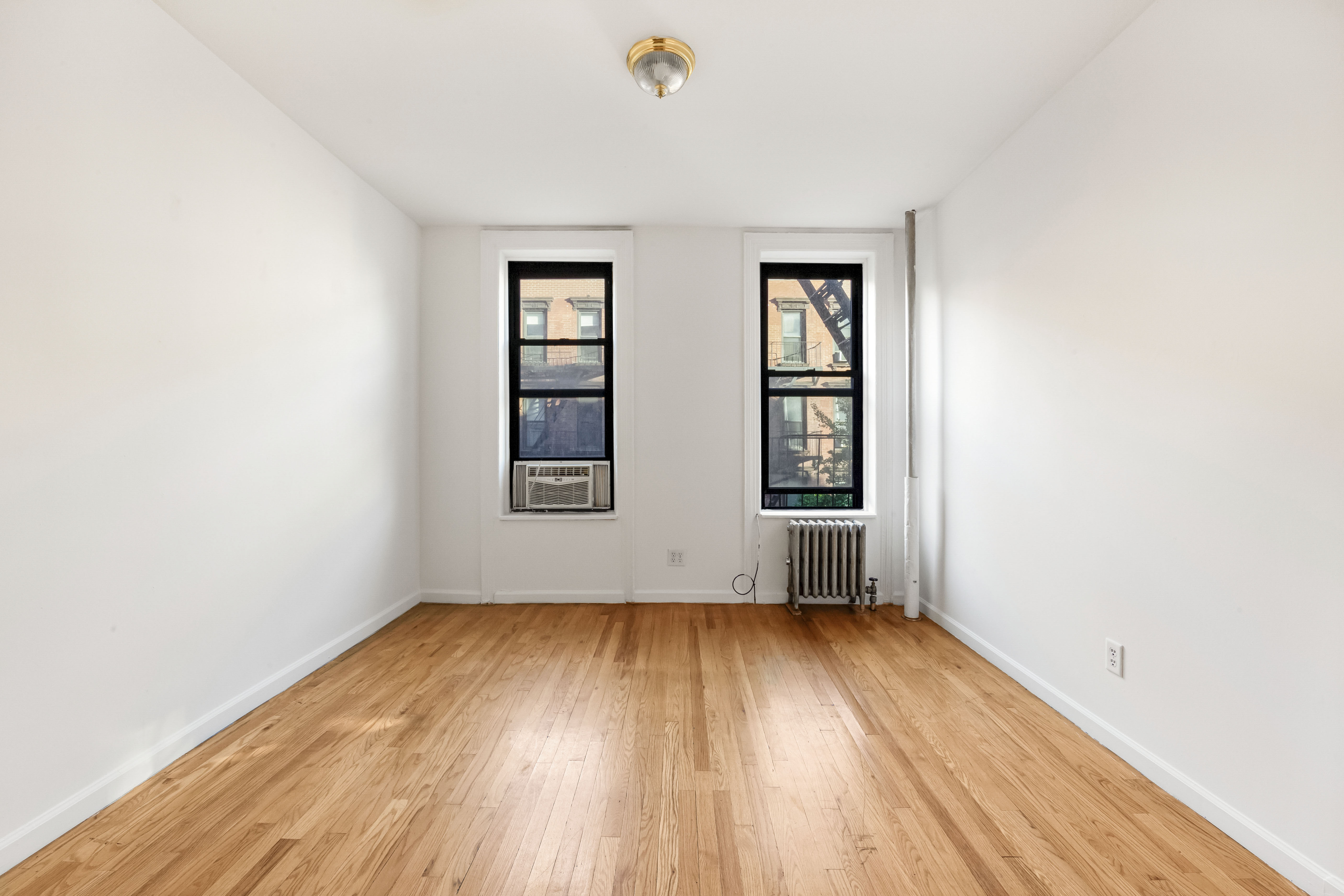142 Sullivan Street, Unit 12 Manhattan, NY 10012 - Photo 6 of 12 an empty room with wooden floor and windows