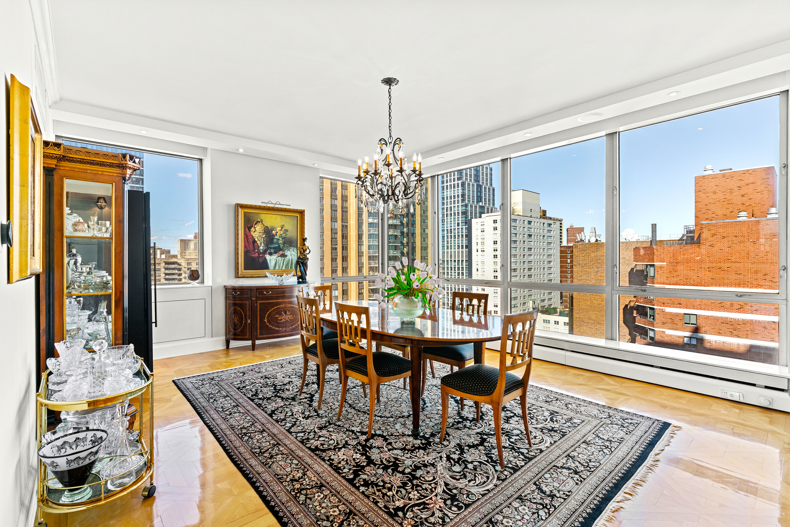 1965 Broadway, Unit 26EF Manhattan, NY 10023 - Photo 13 of 32 a dining room with wooden floor a chandelier a wooden table and chairs