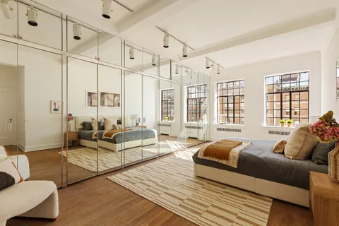 a spacious bedroom with a bed and wooden floor