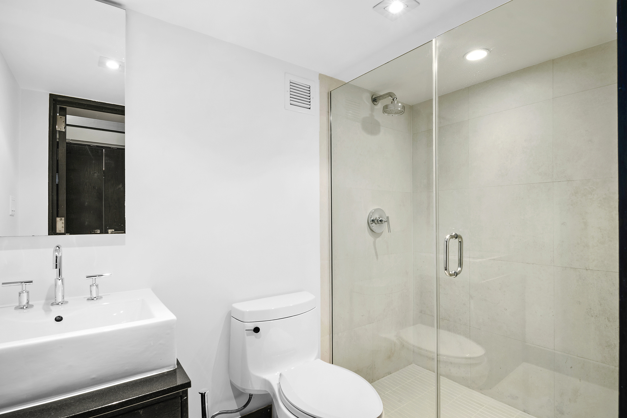 254 Park Avenue South, Unit 3G Manhattan, NY 10010 - Photo 5 of 12 a bathroom with a toilet sink vanity and shower