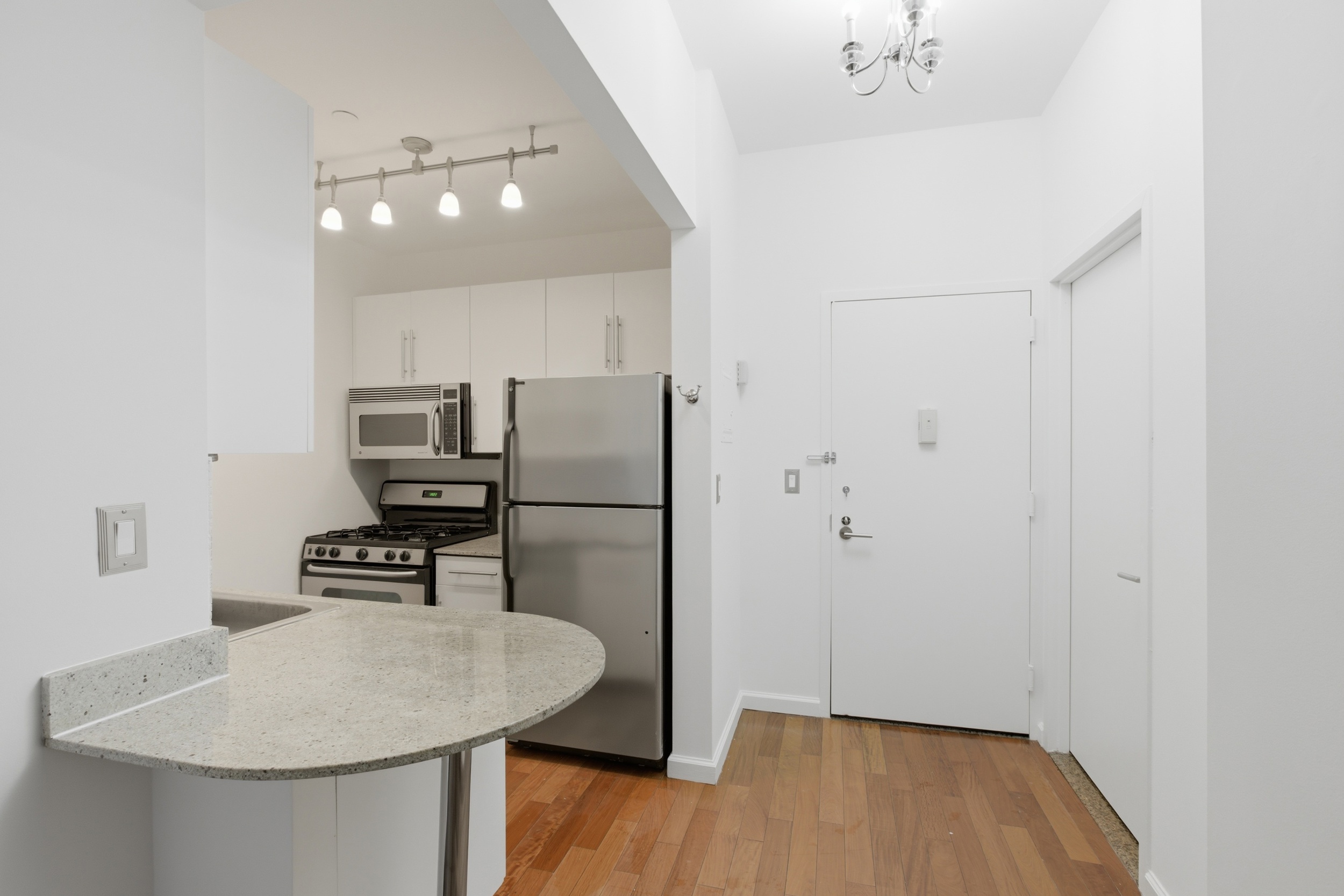 1 Wall Street Court, Unit 406 Manhattan, NY 10005 - Photo 4 of 7 a kitchen with stainless steel appliances a refrigerator and a stove