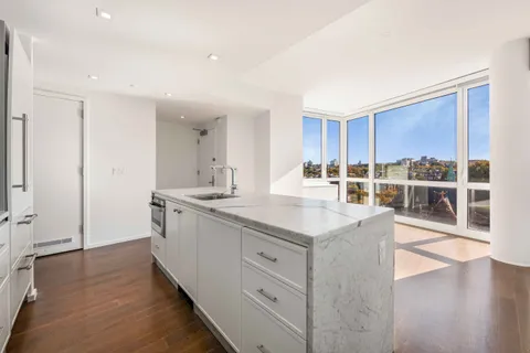 a living room with furniture white walls and kitchen view