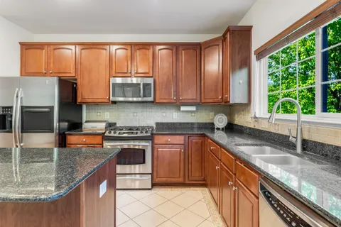 a kitchen with stainless steel appliances granite countertop a sink a stove cabinets counter space and a window