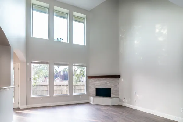 an empty room with wooden floor fireplace and windows