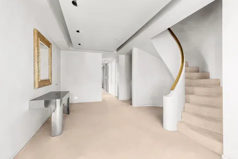 a view of an empty room with stairs and a window