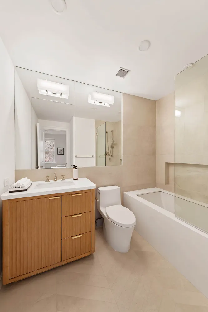 a bathroom with a granite countertop sink mirror vanity bathtub and toilet