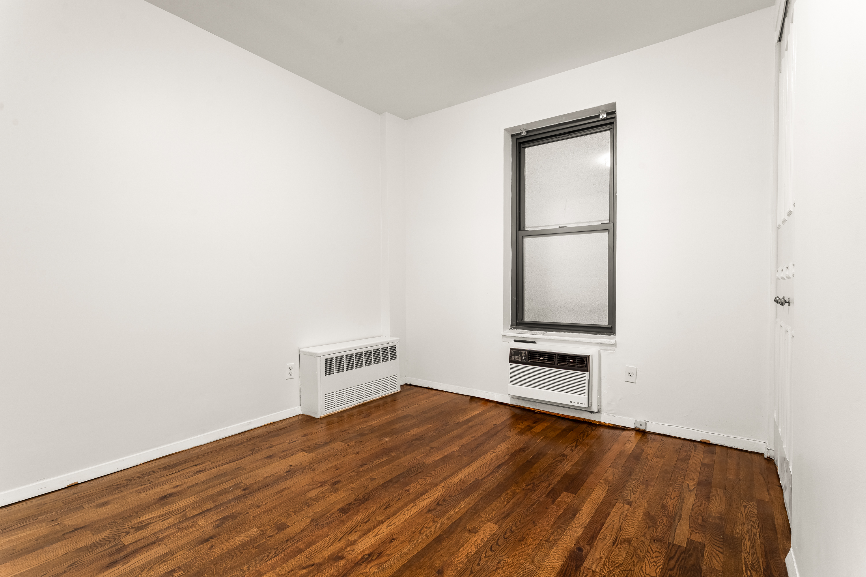 160 East 91st Street, Unit 7N Manhattan, NY 10128 - Photo 10 of 13 a view of an empty room with wooden floor and a window