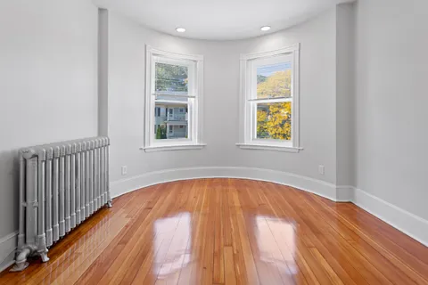 a view of a bedroom with wooden floor and window