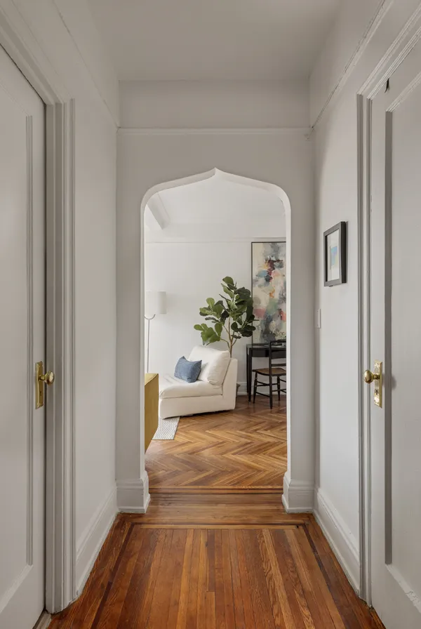 a hallway with wooden floor and a potted plant