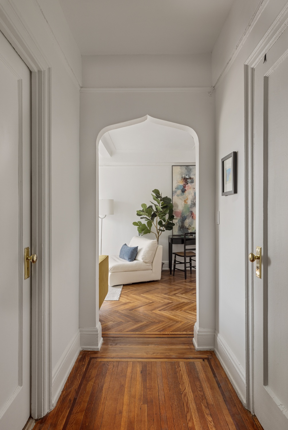 233 West 99th Street, Unit 19A Manhattan, NY 10025 - Photo 1 of 10 a hallway with wooden floor and a potted plant