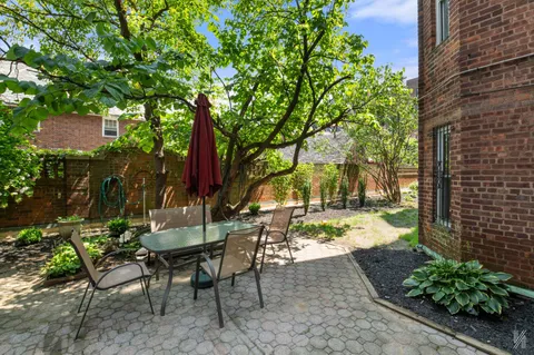 a view of a patio with table and chairs potted plants and large tree