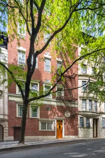 a front view of a house with a tree