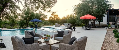 a view of a patio with furniture and table under an umbrella with a barbeque