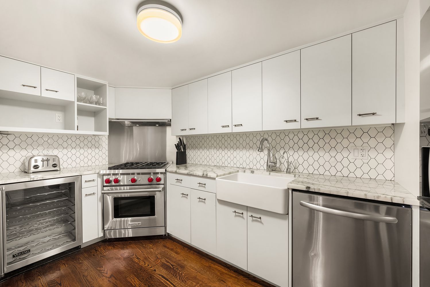 421 Hudson Street, Unit 306 Manhattan, NY 10014 - Photo 5 of 12 a kitchen with stainless steel appliances granite countertop a stove a sink and white cabinets
