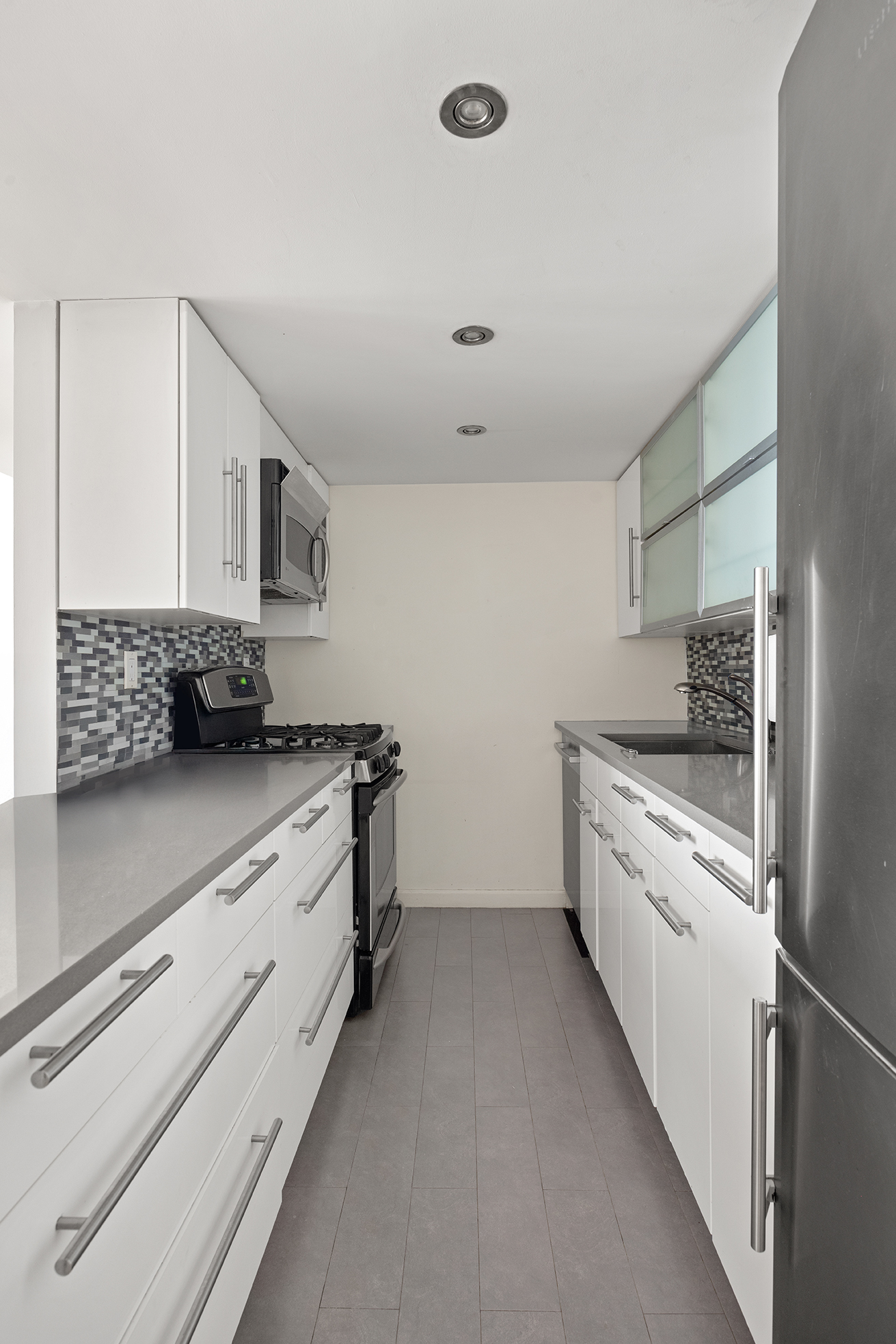 250 Mercer Street, Unit C414 Manhattan, NY 10012 - Photo 8 of 14 a kitchen with granite countertop a sink stainless steel appliances and cabinets