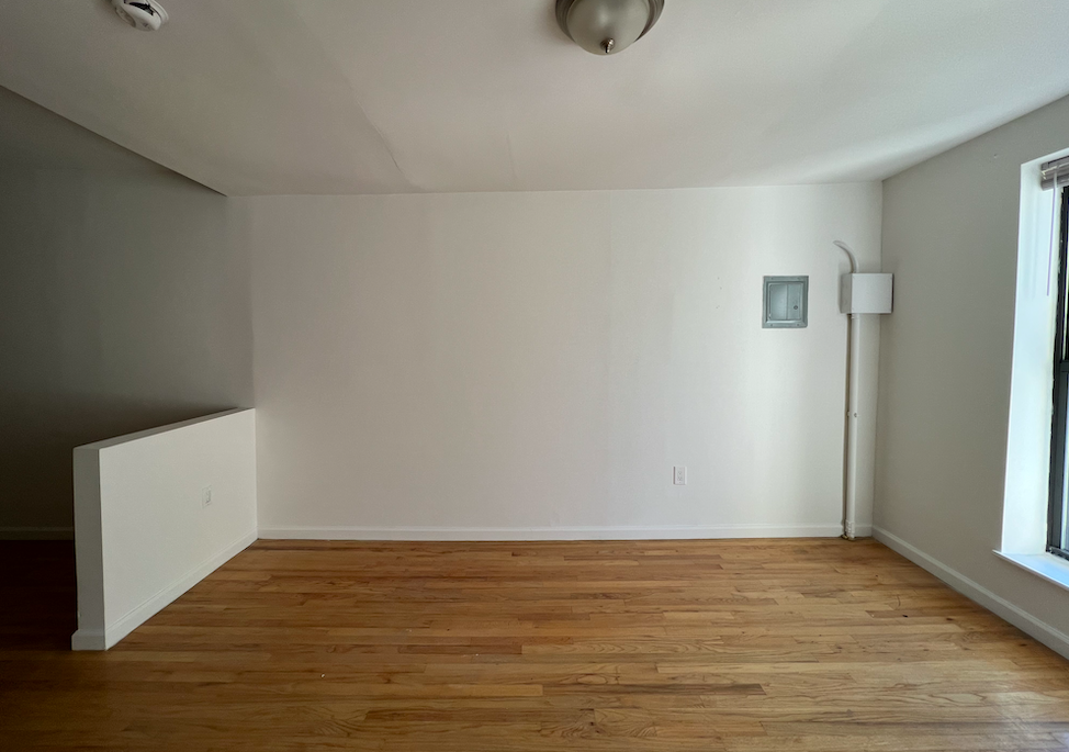 446 West 46th Street, Unit 16 Manhattan, NY 10036 - Photo 7 of 12 a view of an empty room with wooden floor and a window