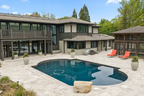 a view of a house with pool and chairs under an umbrella