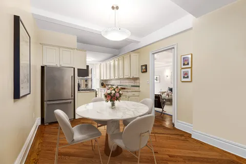 a kitchen with stainless steel appliances granite countertop a dining table chairs refrigerator and microwave