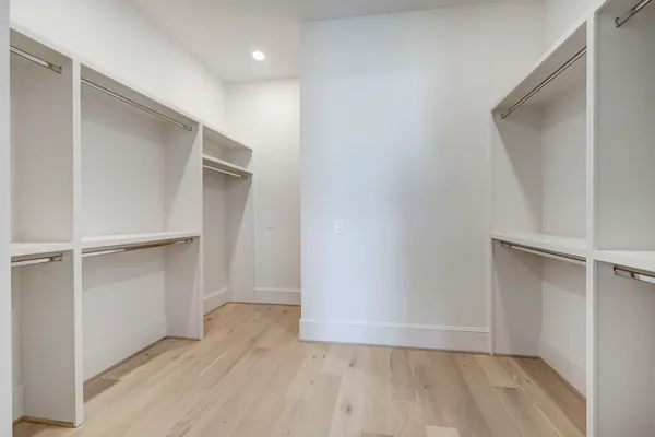 a view of an empty walk in closet with wooden floor
