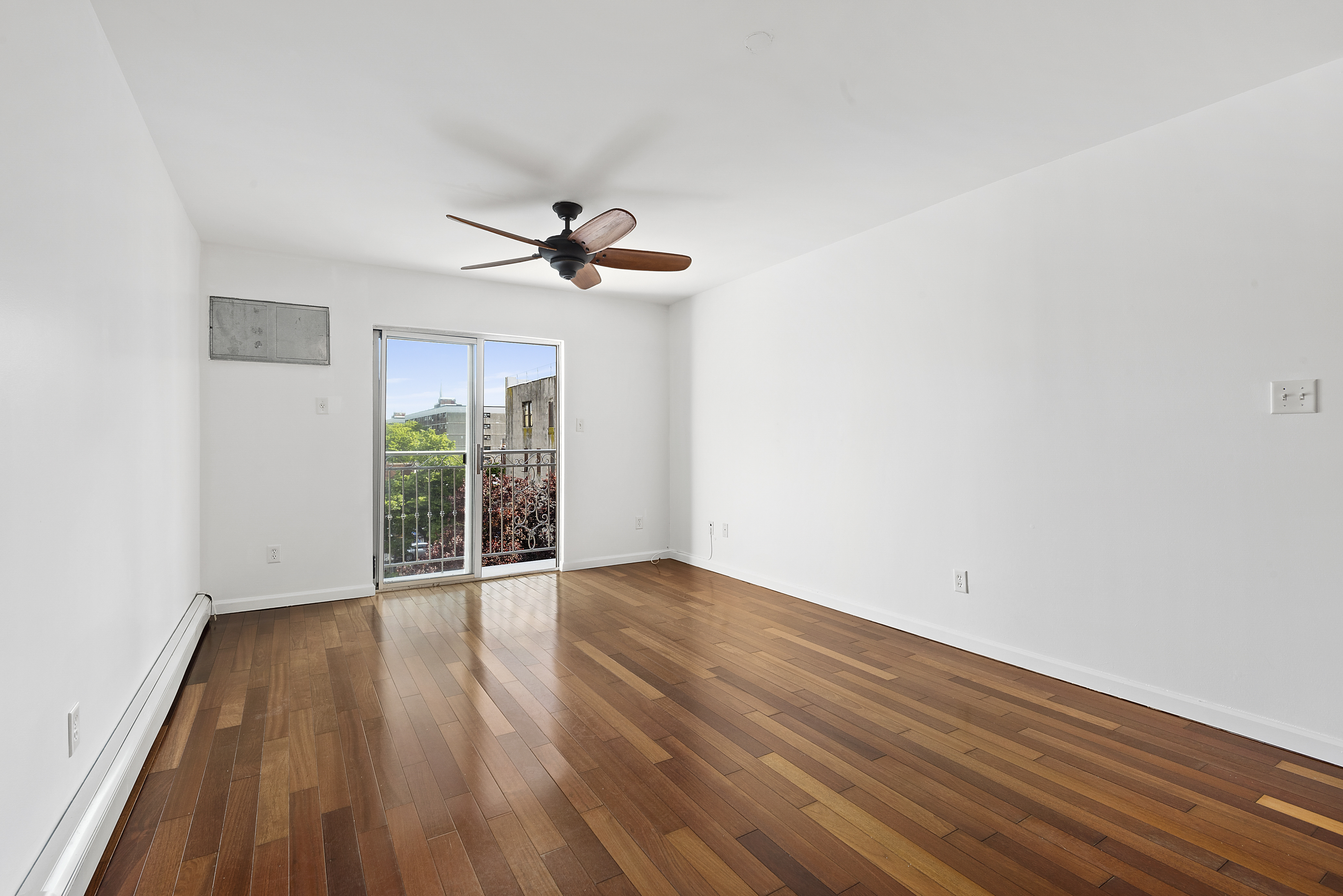 122 Boerum Street, Unit 4R Brooklyn, NY 11206 - Photo 2 of 9 a view of an empty room with wooden floor and a window