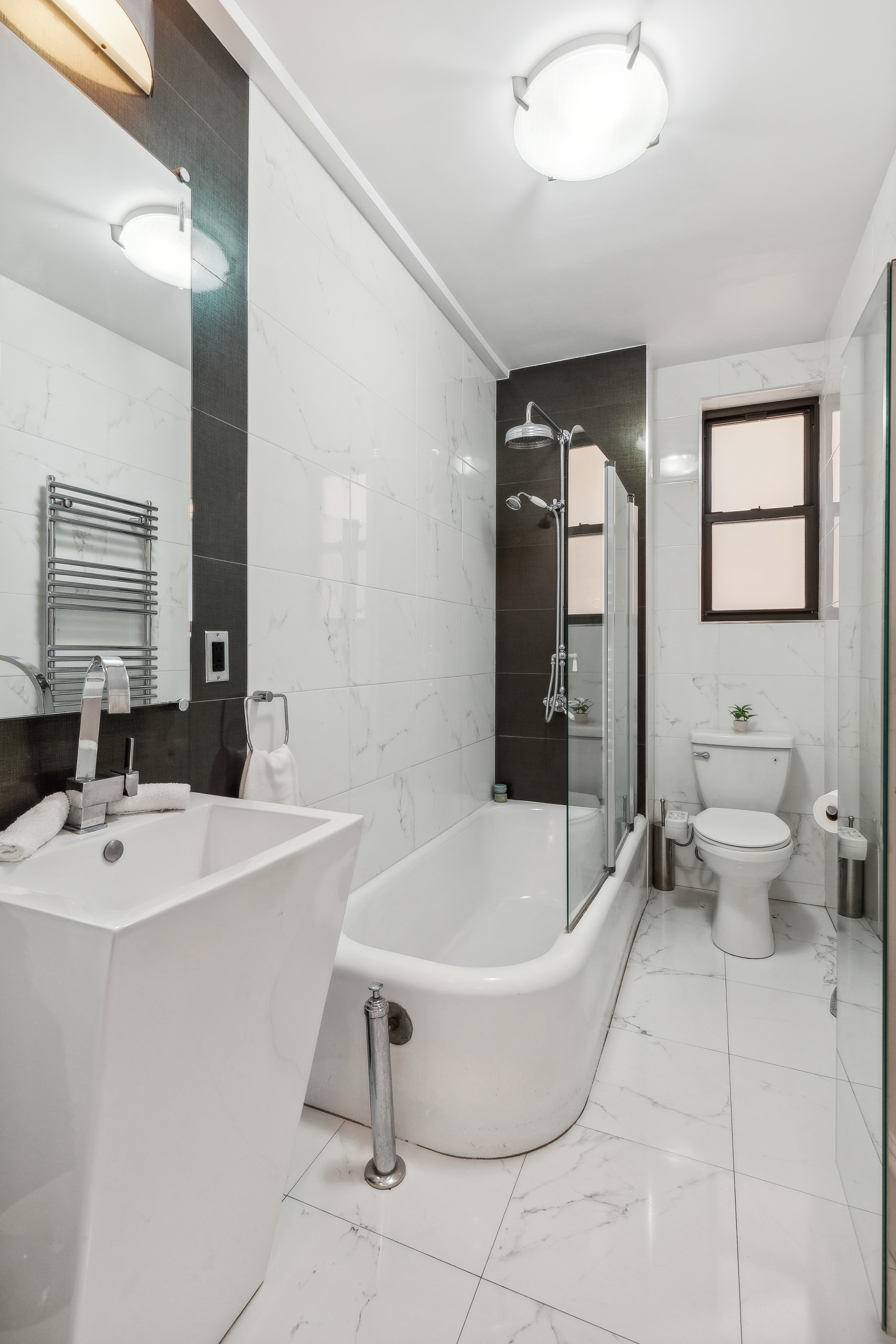 300 Riverside Drive, Unit 5E Manhattan, NY 10025 - Photo 9 of 11 a bathroom with a white tub sink and mirror