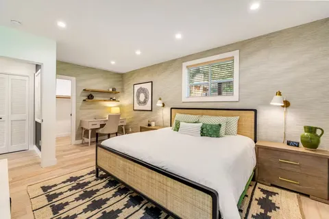 a bedroom with a bed a mirror on dresser and a table