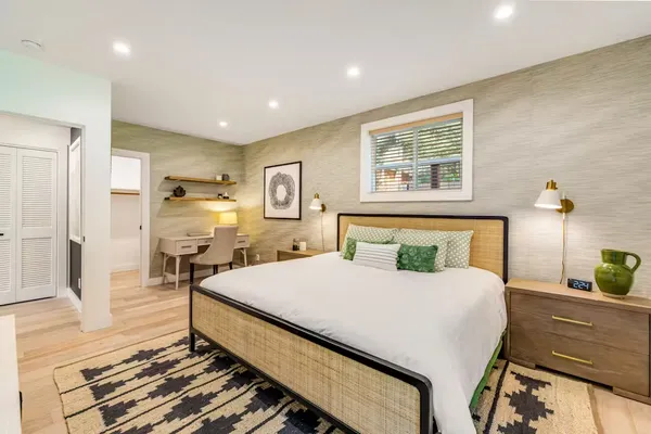 a bedroom with a bed a mirror on dresser and a table