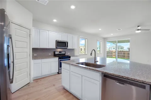 a kitchen with granite countertop white cabinets and stainless steel appliances