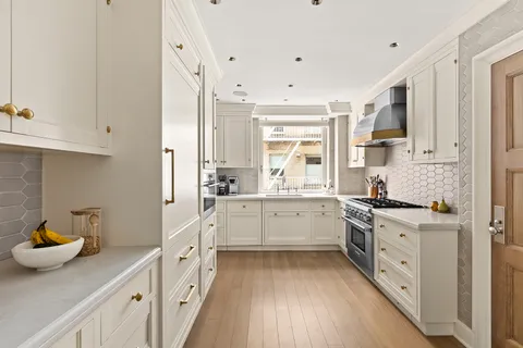 a kitchen with a sink dishwasher stove and white cabinets