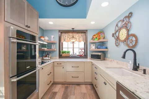 a kitchen with granite countertop stainless steel appliances a sink cabinets and a window