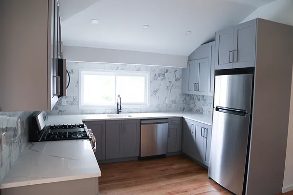 143-86 232nd Street, Unit 1 Queens, NY 11413 - Photo 2 of 5 a kitchen with stainless steel appliances a sink a stove a refrigerator and cabinets