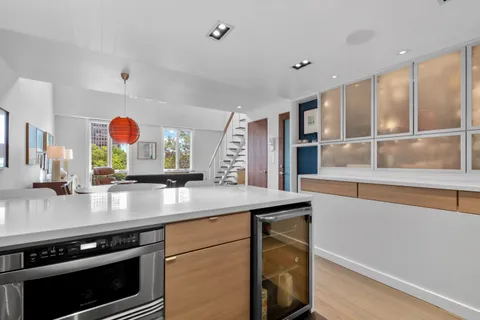 a living room with furniture kitchen view and a wooden floor