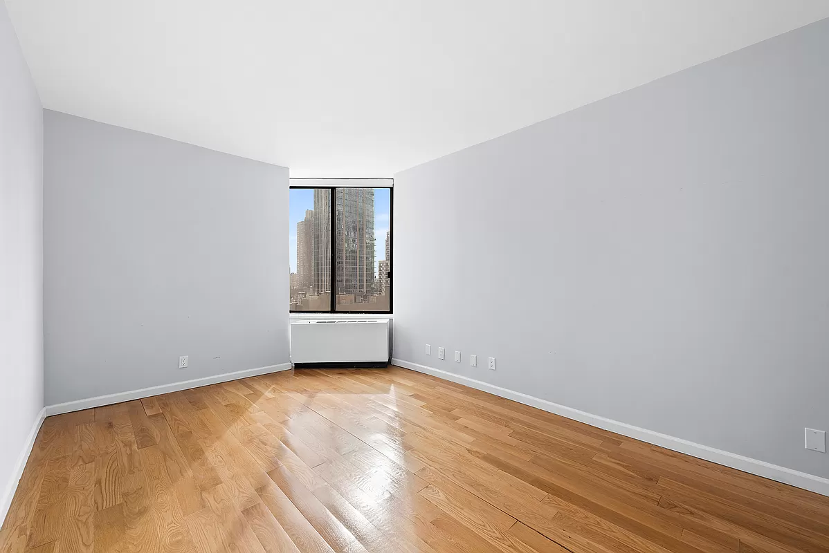 300 East 93rd Street, Unit 14F Manhattan, NY 10128 - Photo 7 of 14 a view of an empty room with wooden floor and a window