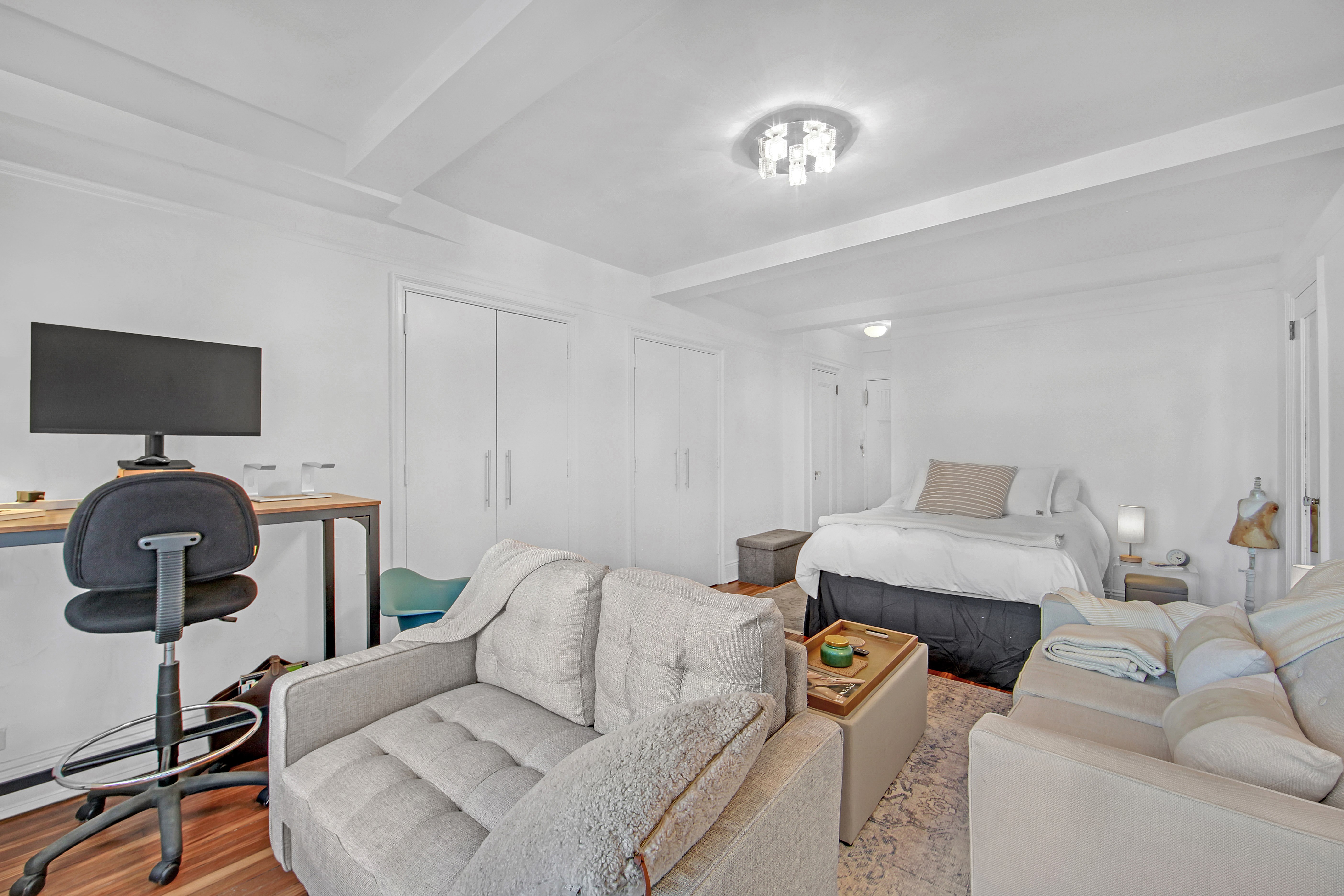 5 Tudor City Place, Unit 539 Manhattan, NY 10017 - Photo 7 of 12 a living room with furniture and a flat screen tv
