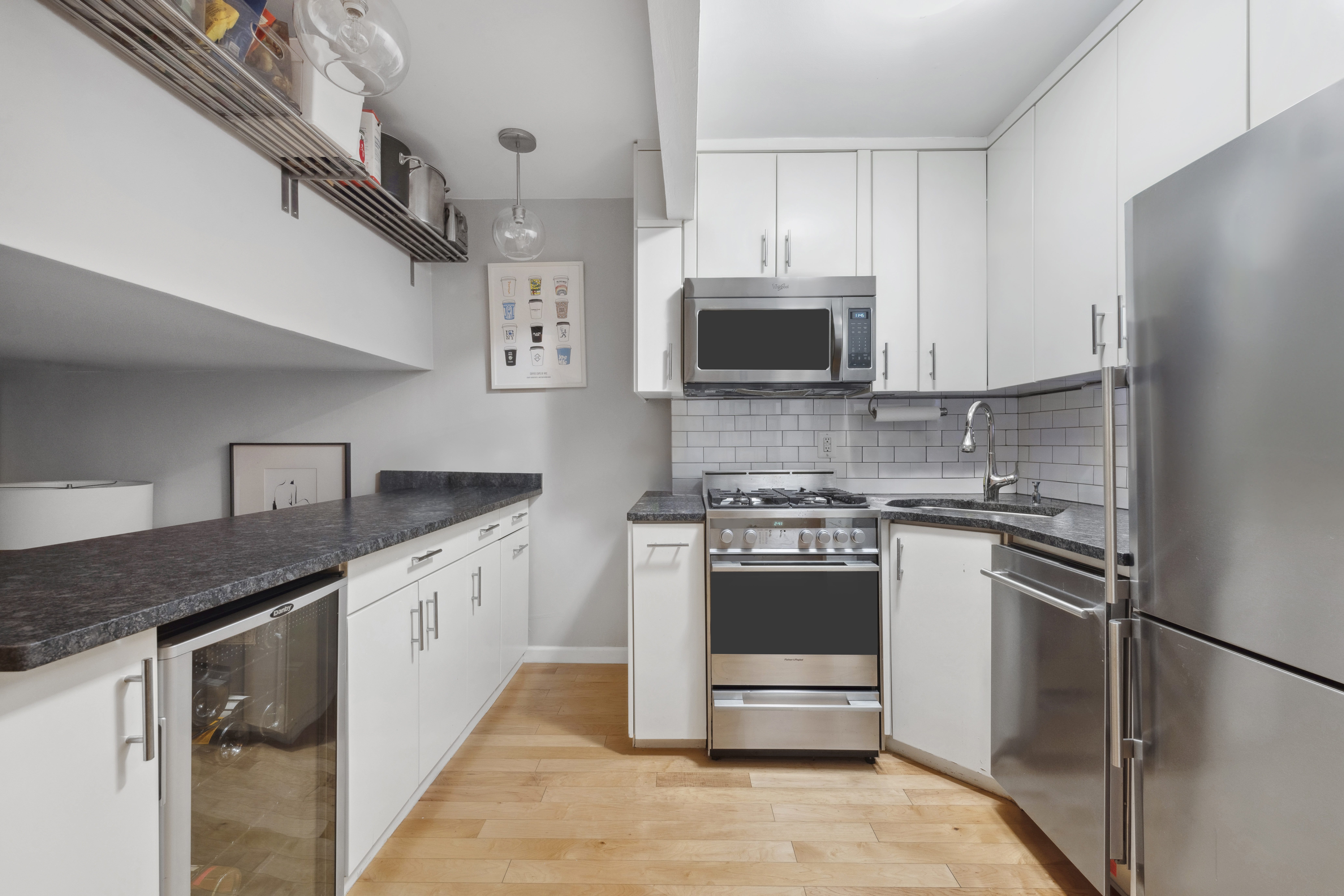 211 Thompson Street, Unit GLD Manhattan, NY 10012 - Photo 5 of 10 a kitchen with stainless steel appliances granite countertop a stove microwave and sink