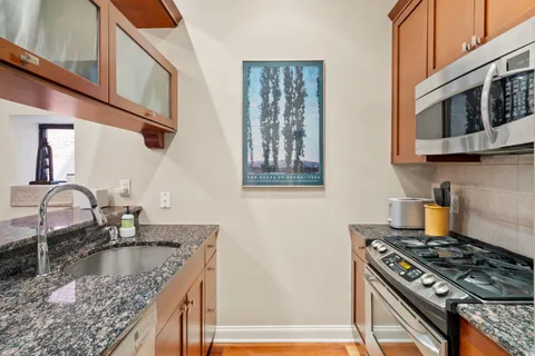 a kitchen with granite countertop a stove top oven cabinetry a sink and a counter