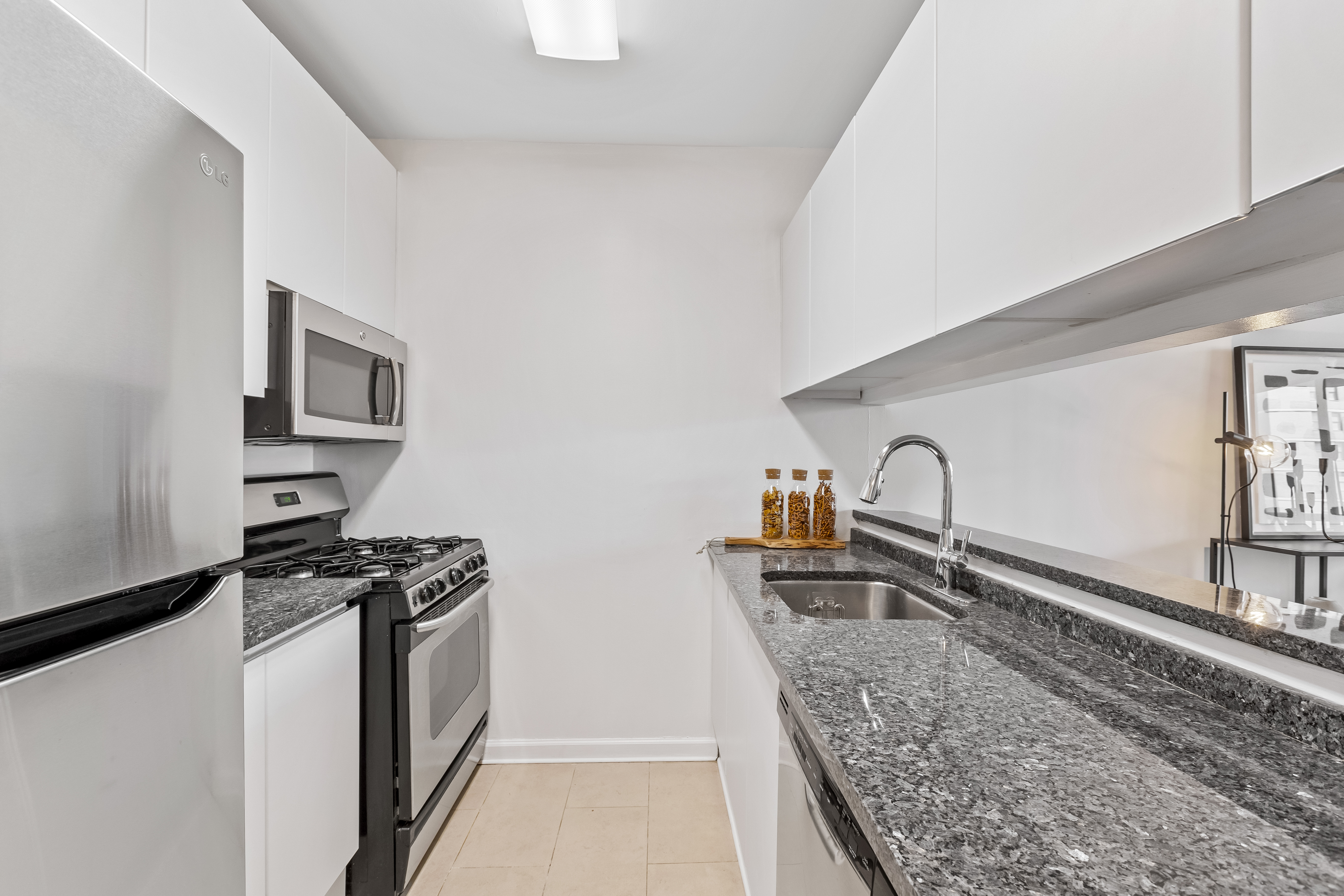 157 East 32nd Street, Unit 8A Manhattan, NY 10016 - Photo 9 of 16 a kitchen with granite countertop a sink stove and cabinets