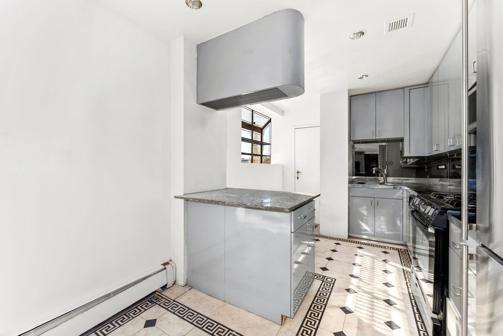 40 Sutton Place, Unit 10M Manhattan, NY 10022 - Photo 6 of 10 a kitchen with granite countertop a sink stove and cabinets