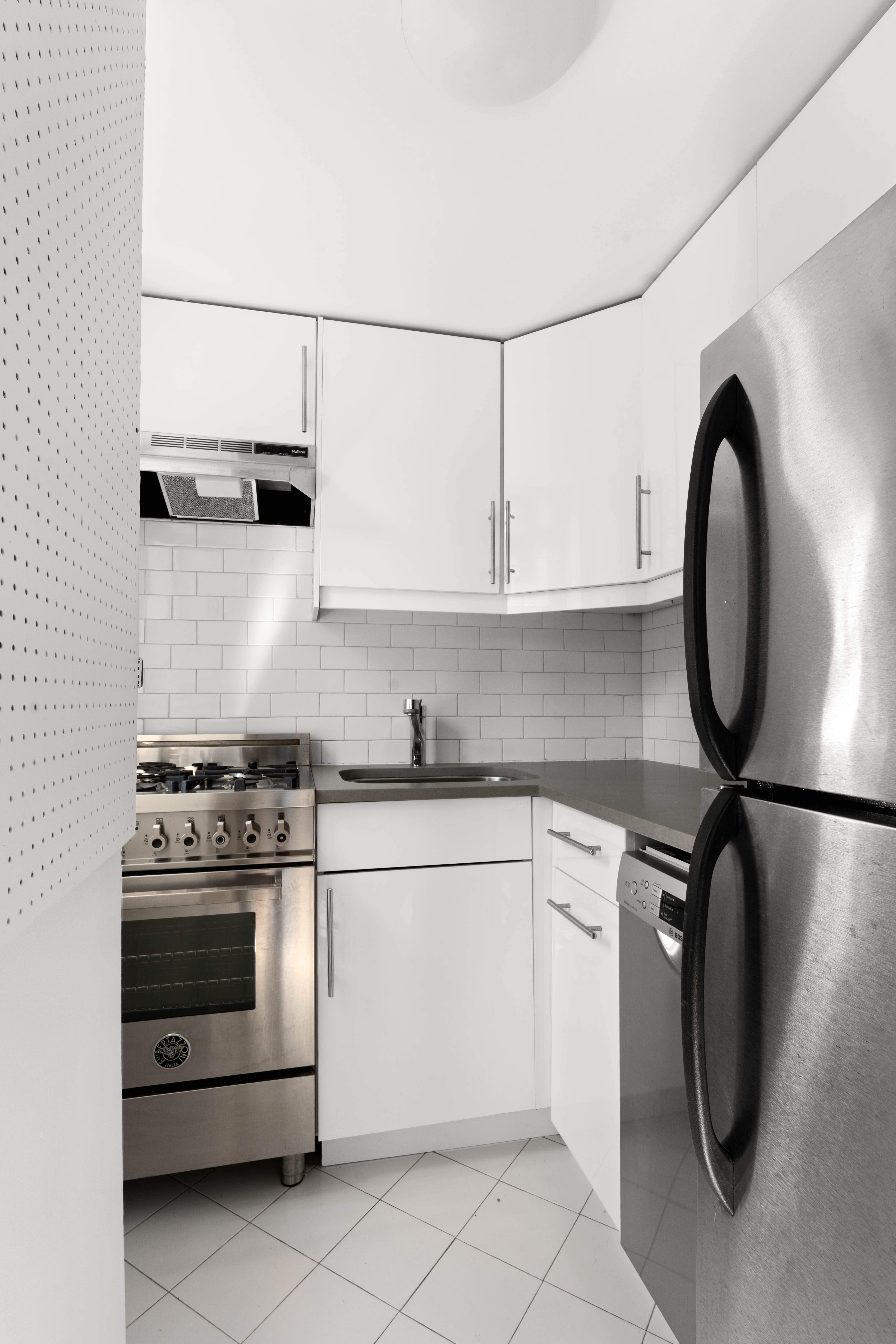 200 East 16th Street, Unit 14K Manhattan, NY 10003 - Photo 3 of 7 a kitchen with stainless steel appliances granite countertop a stove a sink and a microwave