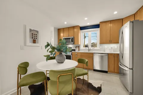 a kitchen with stainless steel appliances granite countertop a refrigerator a sink a stove and white cabinets with wooden floor