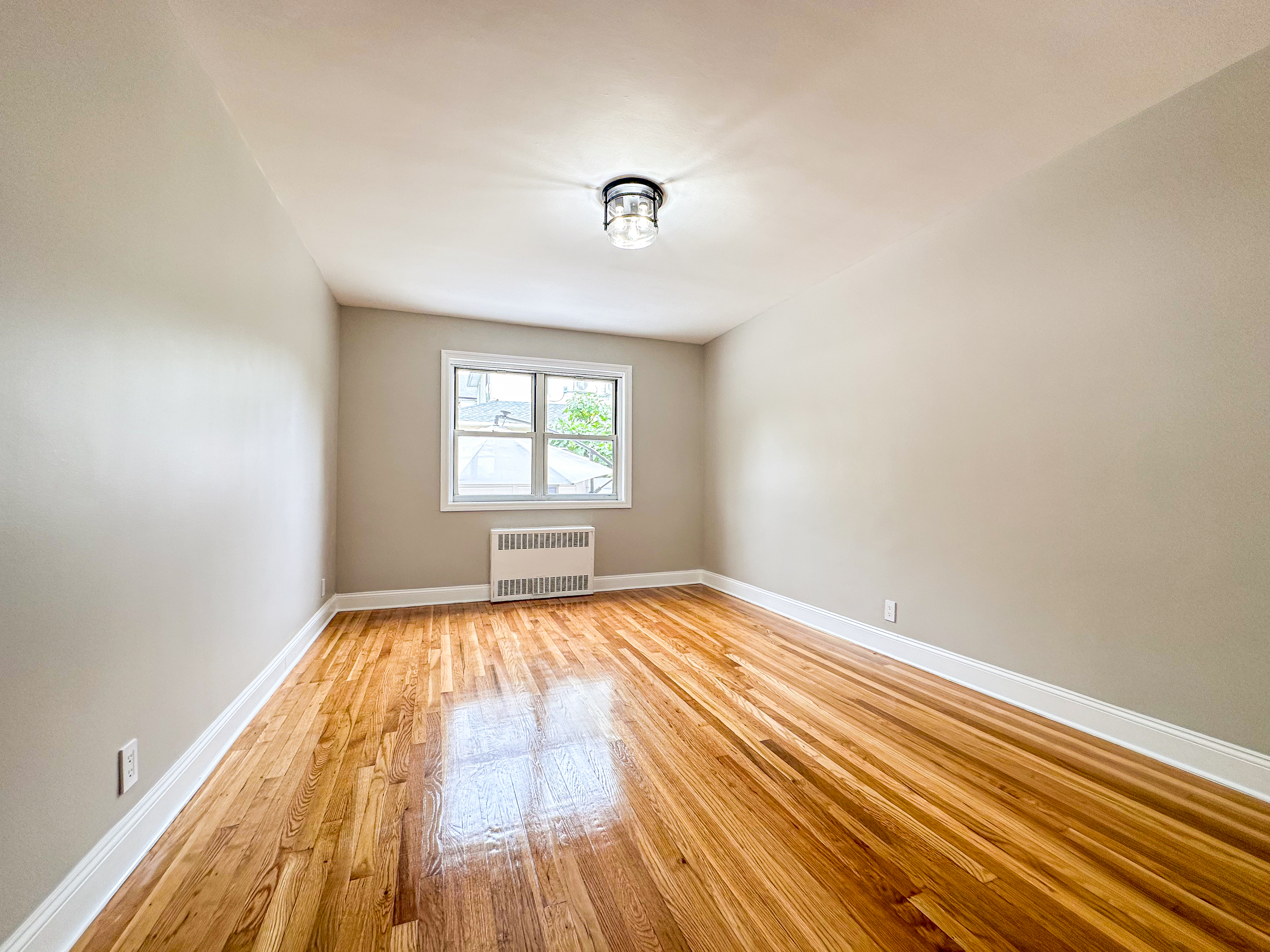 10-01 154th Street, Unit 1 Queens, NY 11357 - Photo 5 of 10 wooden floor in an empty room with a window