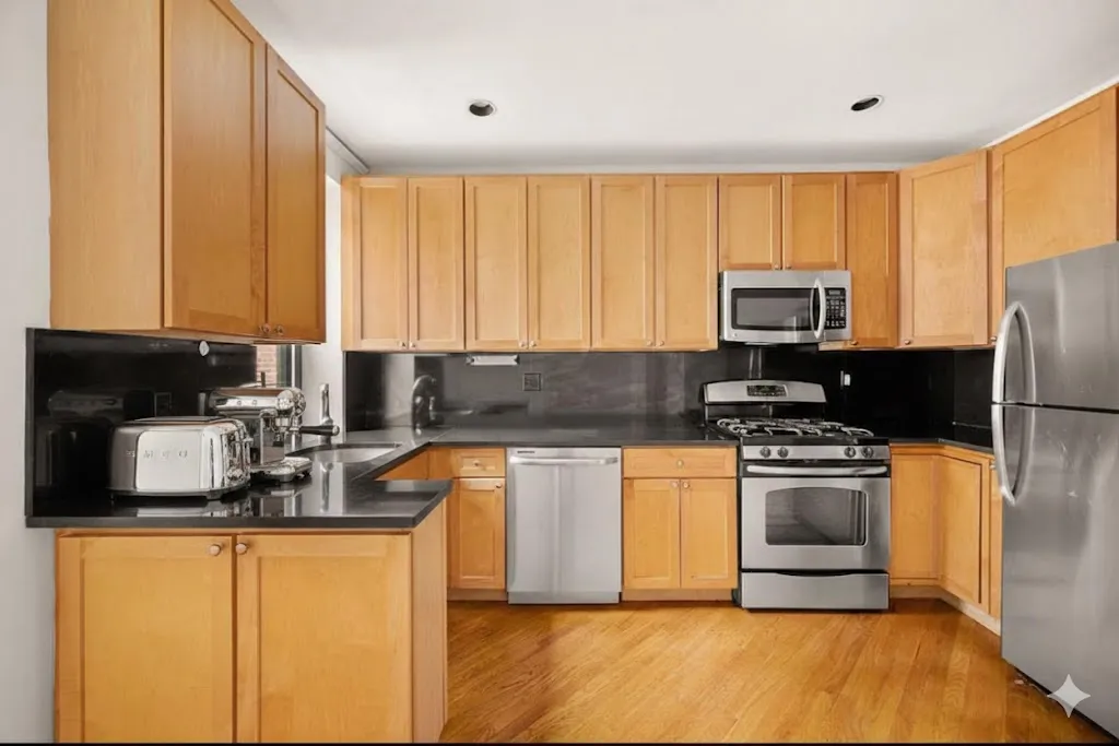 a kitchen with stainless steel appliances granite countertop a stove a sink a microwave a refrigerator and cabinets