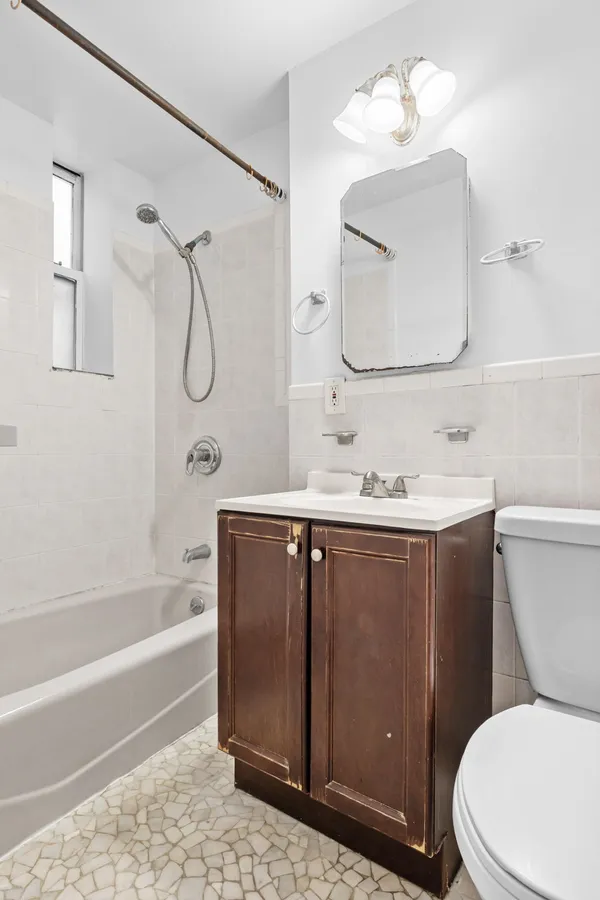 a bathroom with a sink vanity mirror bathtub and toilet