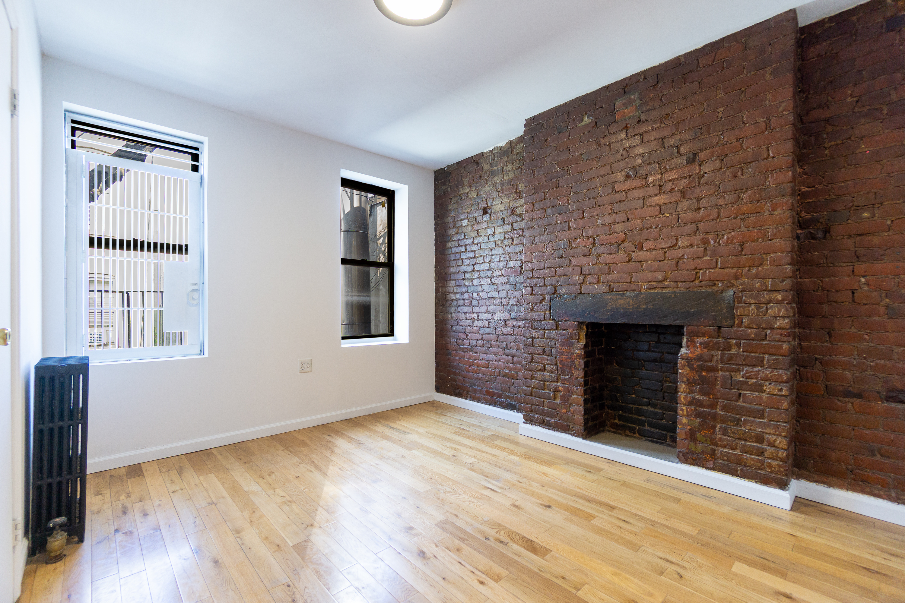 339 East 6th Street, Unit 14 Manhattan, NY 10003 - Photo 3 of 8 a view of empty room with wooden floor and fireplace
