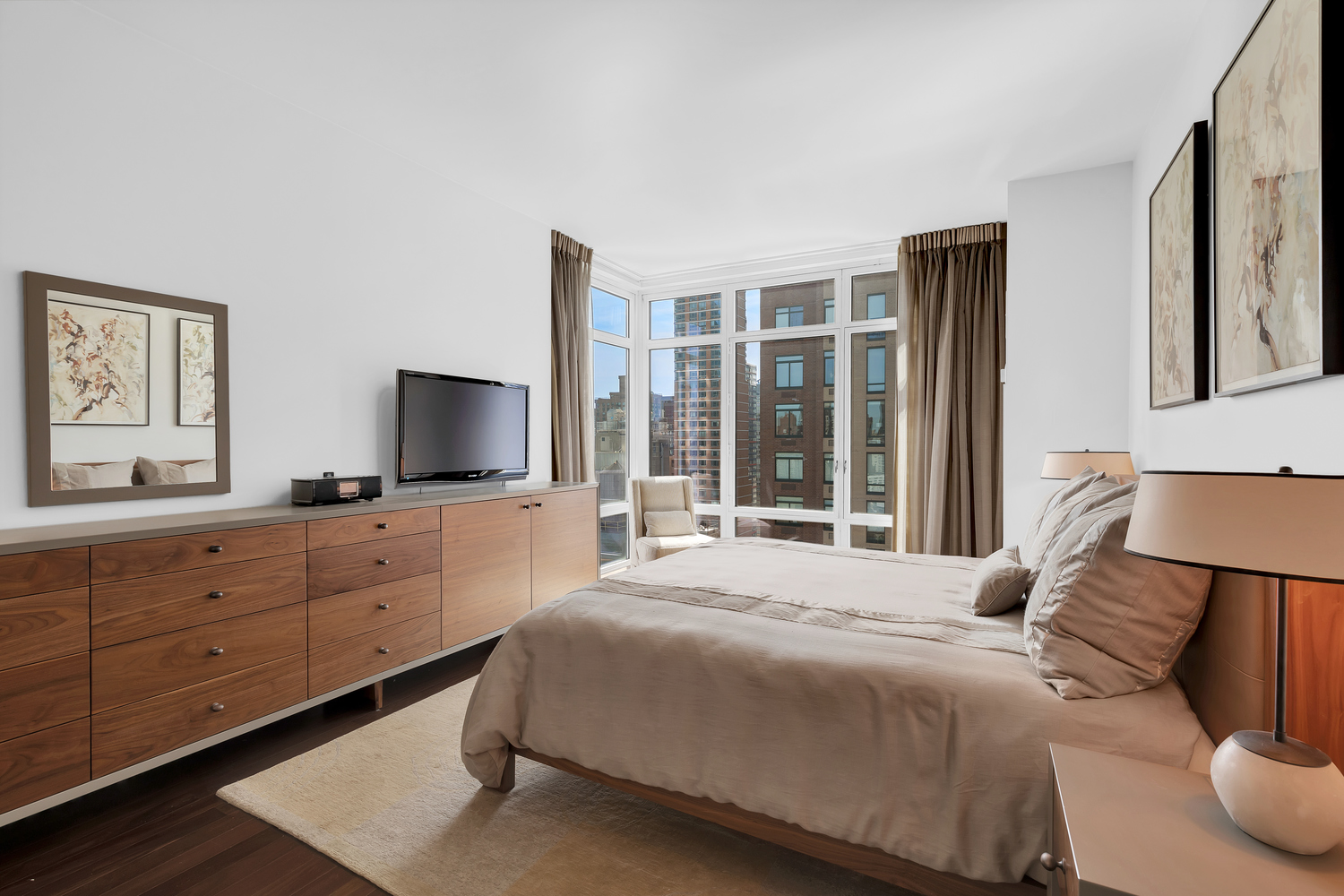 207 East 57th Street, Unit 25B Manhattan, NY 10022 - Photo 9 of 19 a bedroom with a large bed and a flat tv screen on dresser