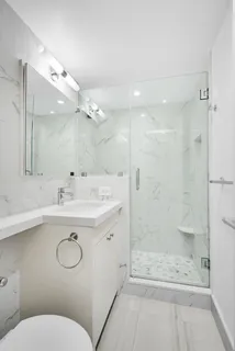 a bathroom with a sink a toilet a mirror and shower