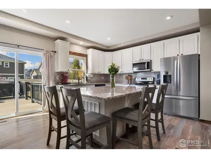 a kitchen with kitchen island a dining table chairs stainless steel appliances and cabinets