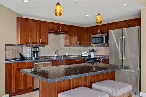 a kitchen with stainless steel appliances granite countertop a sink refrigerator stove and microwave