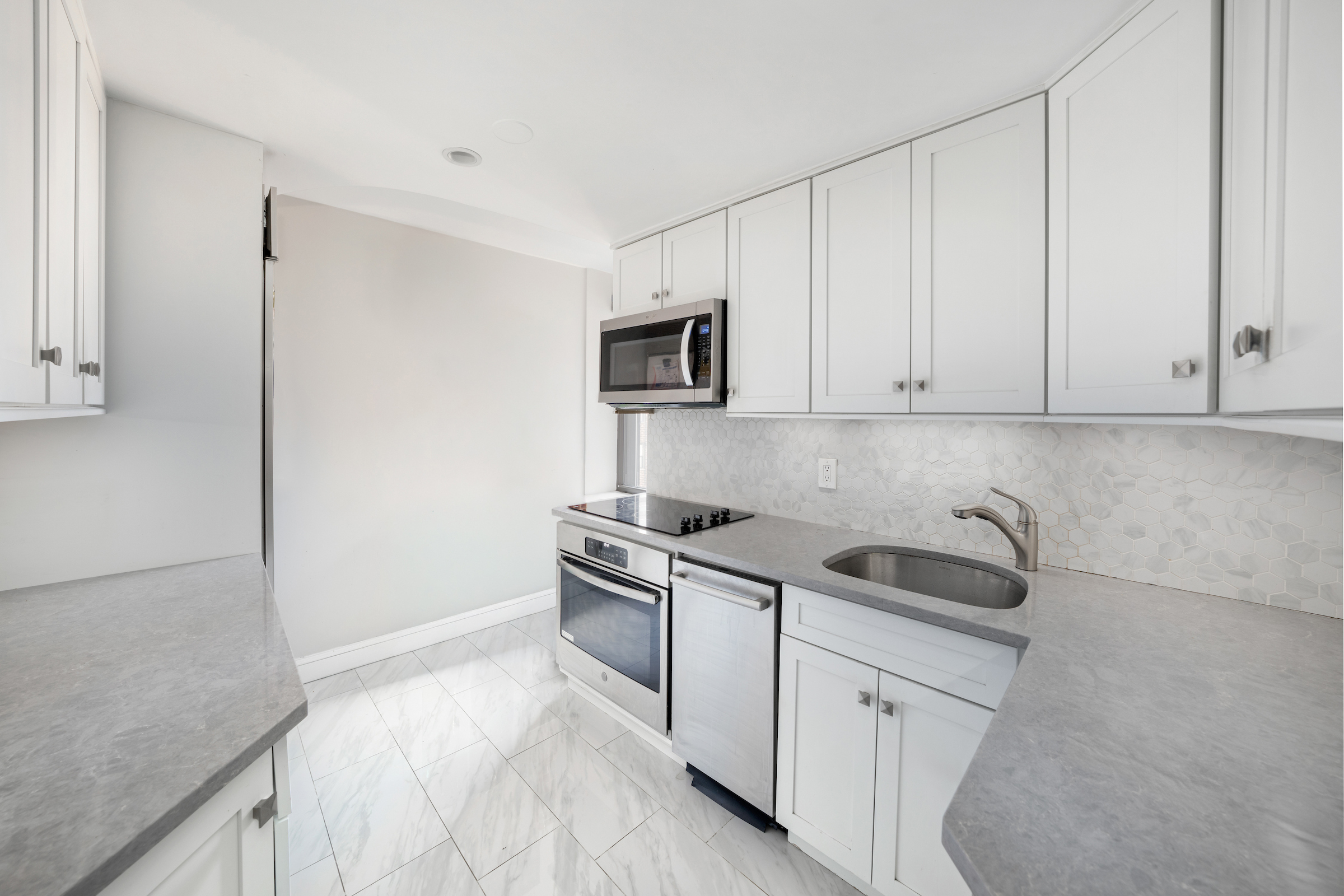 2 Tudor City Place, Unit 11KN Manhattan, NY 10017 - Photo 3 of 14 a kitchen with granite countertop white cabinets and stainless steel appliances